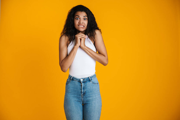 Surprised shocked young african woman wearing casual clothing standing isolated over yellow background - Foto, afbeelding