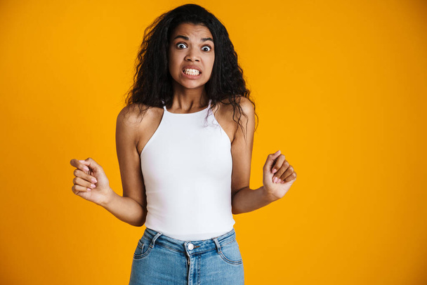 Surprised shocked young african woman wearing casual clothing standing isolated over yellow background - Foto, Bild