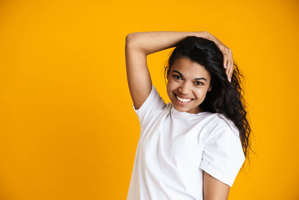 Attractive happy young african woman wearing casual clothing standing isolated over yellow background - Fotoğraf, Görsel