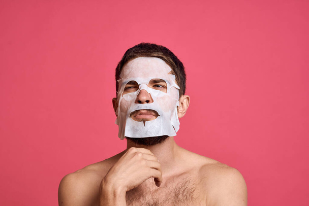 man in cleansing mask on pink background gesturing with hands naked torso cropped view - Fotó, kép