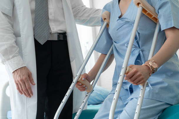Arzt versorgt Patientin auf Krücken im Krankenhaus - Foto, Bild