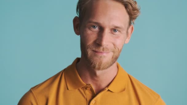 Giovane attraente uomo barbuto biondo con fiducia agitando sì sulla macchina fotografica su sfondo colorato - Filmati, video