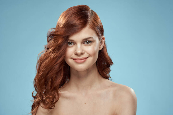 美しい女性巻き長い髪滑らかな髪型裸の肩化粧品ケア青の背景 - 写真・画像