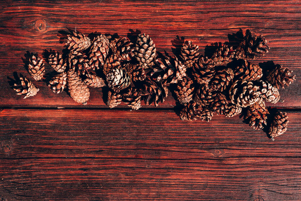 Многие сосновые шишки лежат на деревянном столе из красного дерева. Осенний текстурированный фон и много места для текста и дизайна. - Фото, изображение