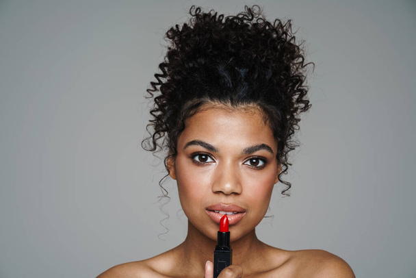 Image of shirtless african american woman posing with lipstick isolated over grey wall - 写真・画像