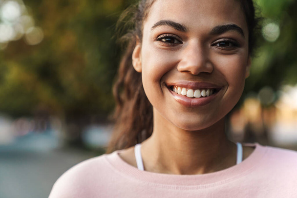 Image of happy african american girl smiling while walking in summer park - Fotó, kép