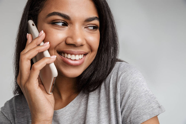 Piękna Afrykanka rozmawia przez telefon na szarym tle - Zdjęcie, obraz