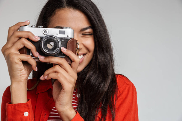 Retrato de uma menina americana muito africana sorridente tirando foto com uma câmera isolada sobre fundo cinza - Foto, Imagem
