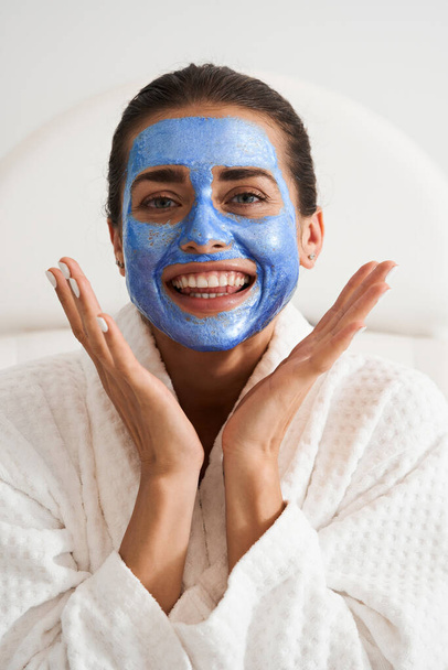 Woman with clay mask on surprised face - Photo, image