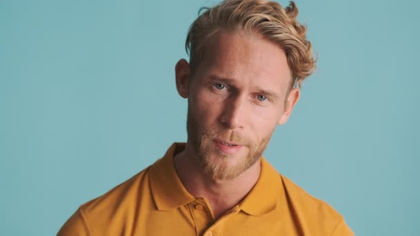 Young blond bearded man tiredly posing on camera over colorful background - Metraje, vídeo