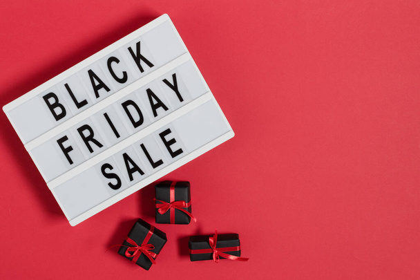 Lightbox with black Friday text and presents top view on red background. Black Friday template for ad design of banners and flyers. Background for sale leaflet design. - 写真・画像