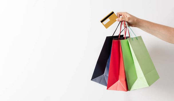 白い背景にカラフルな紙のショッピングバッグやクレジットカードの女性の手を保持グループ。ショッピングバナーのコンセプト. - 写真・画像