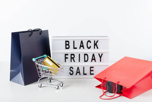 Lightbox with black Friday text, shopping cart with credit cart and shopping bags over white background. Black Friday sale concept. - Foto, immagini