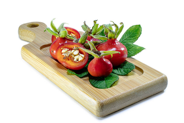 Rosehip berries on a wooden bamboo board. Natural natural vitamins. Ingredients for tea. Medicine and health - Photo, Image