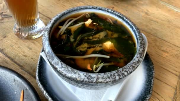 Miso soup in the big ceramic bowl. It is traditional japanese food. Main ingredients are miso paste, tofu, wakame seaweed and shiitake mushrooms. - Footage, Video