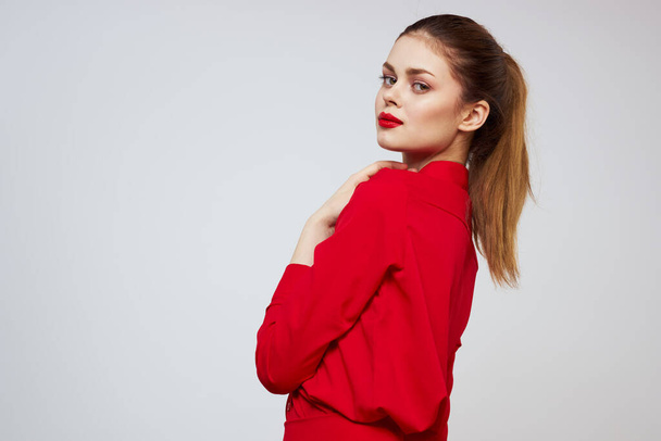 A beautiful girl with red lips and a shirt on a light background gestures with her hands - Foto, Bild