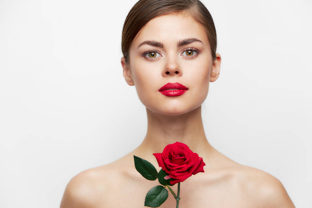 Κυρία με τριαντάφυλλο Κοιτάζει μπροστά κόκκινα χείλη, διαυγές δέρμα φως πολυτέλεια  - Φωτογραφία, εικόνα