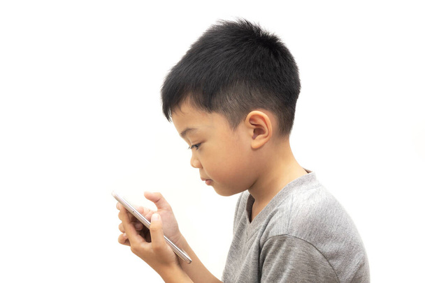 Портреты азиатского мальчика с играющим смартфоном на белом фоне, Счастливое время - Фото, изображение