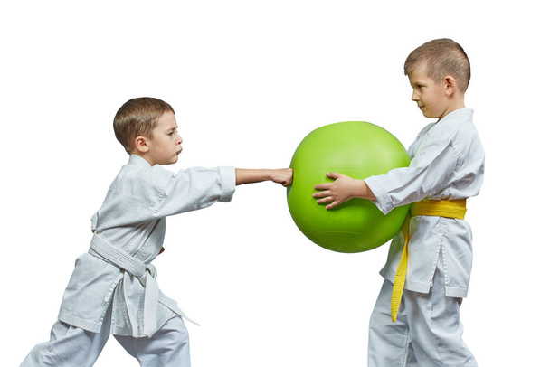 Σε λευκό φόντο, δύο αθλητές προπονούνται για να χτυπήσουν την πράσινη μπάλα με το χέρι του. - Φωτογραφία, εικόνα