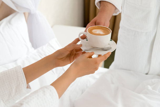 Primer plano de un hombre trayendo café a su novia acostada en la cama - Foto, imagen