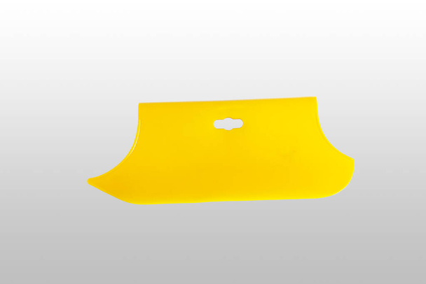 Gele plastic spatel voor behang. Een close-up. Geïsoleerd op lichtgrijze achtergrond. - Foto, afbeelding