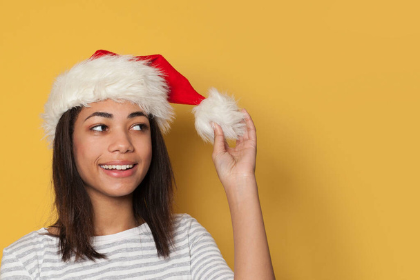 Black woman in Santa hat on yellow background - Photo, Image
