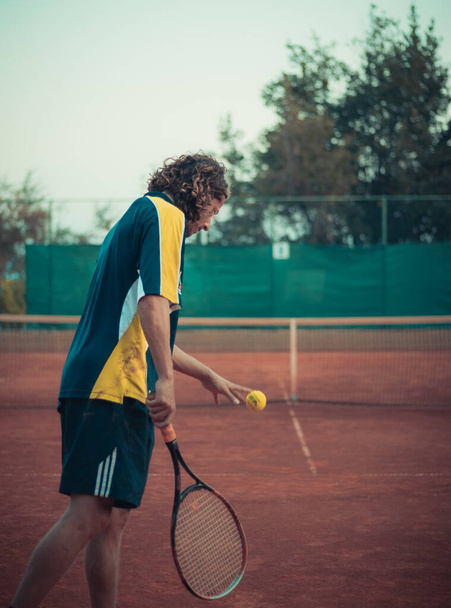 Сплит Хорватия Сентябрь 2020 Вид сзади на человека, держащего ракетку и мяч, готовящегося служить во время игры в теннис на поле из оранжевой глины - Фото, изображение