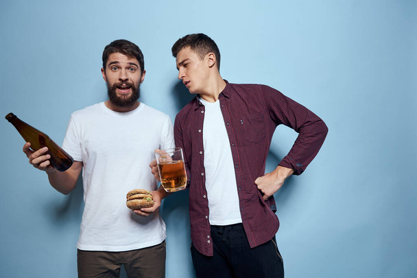 Two cheerful drunk friends drinking beer lifestyle emotions on a blue background - Foto, Imagen