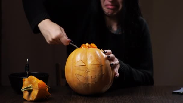 Young brunette woman carves a pumpkin for Halloween Preparation for the holiday - Felvétel, videó