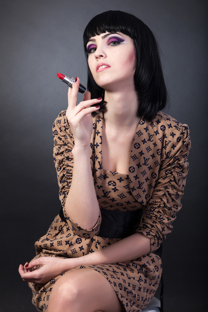 Brunette woman holding a red lipstick - Photo, Image