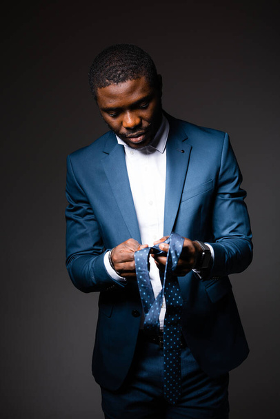 Male African American businessman tying tie - Fotó, kép