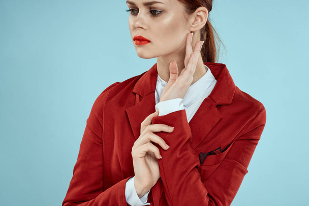 Mujer elegante en chaqueta roja brillante maquillaje labios confianza en sí mismo recortado ver fondo azul - Foto, Imagen