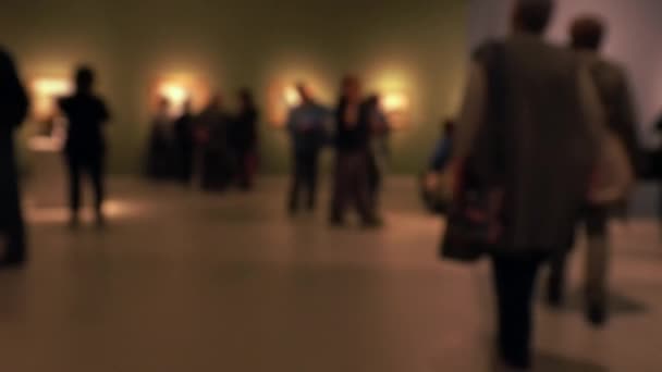 Sanat galerisi ziyareti sırasında yürüyen insanların görüntüsü. Kasıtlı olarak bulanık etki gösteren bir arka plan. 4K - Video, Çekim