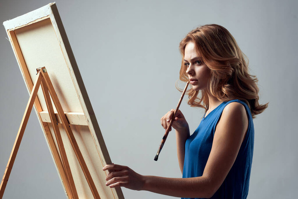 Woman artist with brush paint on easel art hobby light background - Photo, image