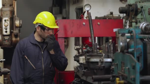 Trabajador de fábrica hablando por radio portátil mientras inspecciona piezas de maquinaria - Imágenes, Vídeo