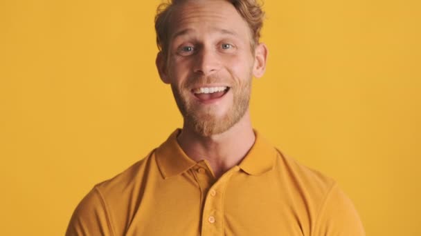 attrayant gai blond barbu homme heureux d'accord sur la caméra sur fond coloré - Séquence, vidéo