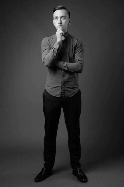 Estúdio tiro de jovem empresário bonito vestindo botão para baixo camisa contra fundo cinza em preto e branco - Foto, Imagem