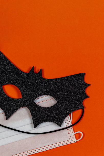 Máscara de Halloween negro y máscara de protección médica sobre fondo naranja - Foto, Imagen
