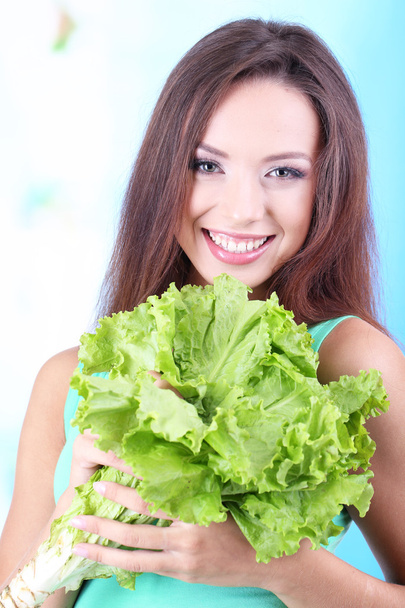 Beautiful girl with fresh salad on blue background - Valokuva, kuva