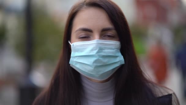 Sekarotuisen naisen muotokuva kaupungin kaduilla päivällä, kasvojen naamio toisen aallon karanteenikoronavirus COVID-19 pandemiaa vastaan - Materiaali, video