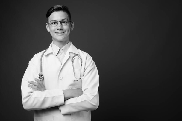 Stüdyoda, siyah ve beyaz olarak gri arka planda gözlük takan genç ve yakışıklı bir doktorun fotoğrafı. - Fotoğraf, Görsel