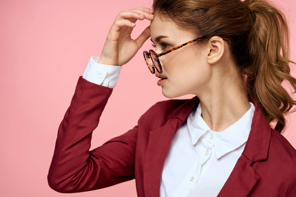 Elegante vrouw in rode jas bril kantoor manager roze achtergrond - Foto, afbeelding