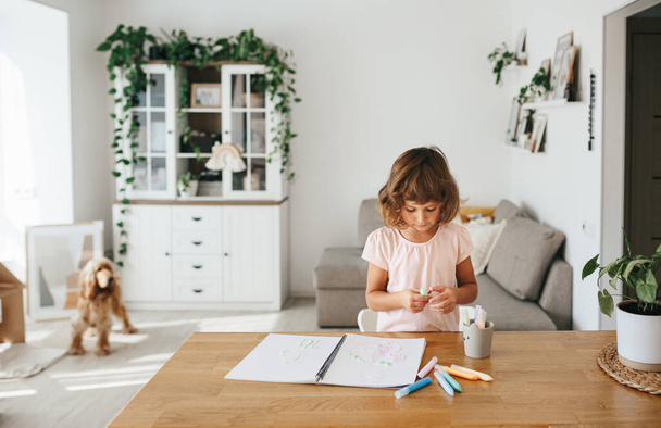 Cute happy little girl, adorable preschooler, 5 years child painting at the table in a white living room at home. Home schooling concept - Foto, Bild
