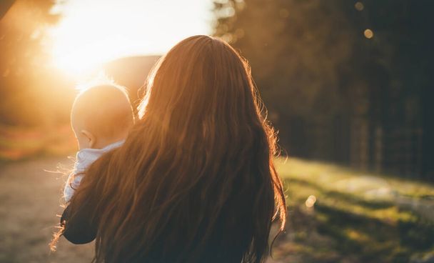 Maman floue avec enfant se tient sur la montagne au coucher du soleil. - Photo, image