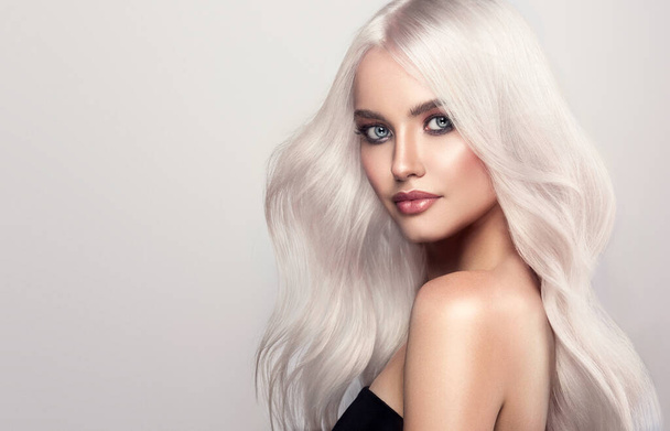 Mooi meisje met haarkleuring in ultra blond. Stijlvolle kapsel krullen gedaan in een schoonheidssalon. Mode, cosmetica en make-up - Foto, afbeelding