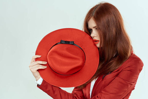 Елегантна жінка в червоній куртці тримає довге волосся обрізане світле тло
 - Фото, зображення