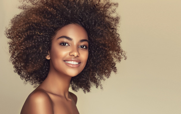Retrato de belleza de mujer afroamericana con piel limpia y saludable sobre fondo beige. Sonriente soñadora hermosa afro girl.Curly pelo negro - Foto, Imagen