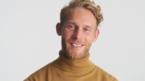 Przystojny blondyn brodaty mężczyzna szczęśliwie pozowanie przed kamerą na białym tle - Materiał filmowy, wideo