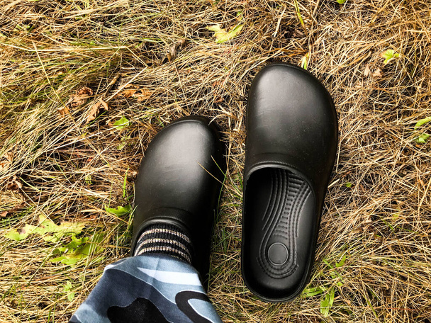 На одній нозі носять чорні гумові накладки. взуття на сухій траві. осінні прогулянки по лісу. волога трава після дощу. захист ніг і шкарпеток від мокрого і холодного ґрунту
 - Фото, зображення