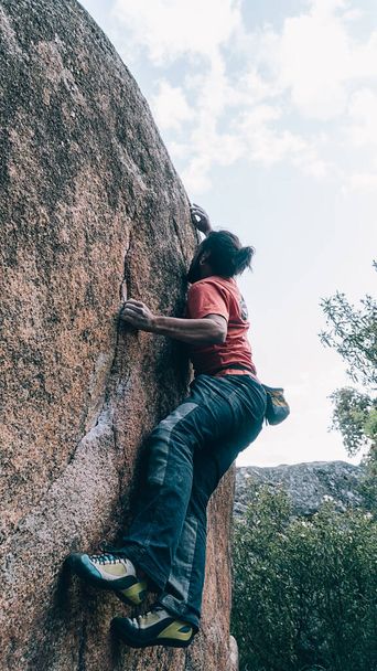 Stockfoto van onherkende man doet moeite om de top van een rots te bereiken tijdens het klimmen. - Foto, afbeelding